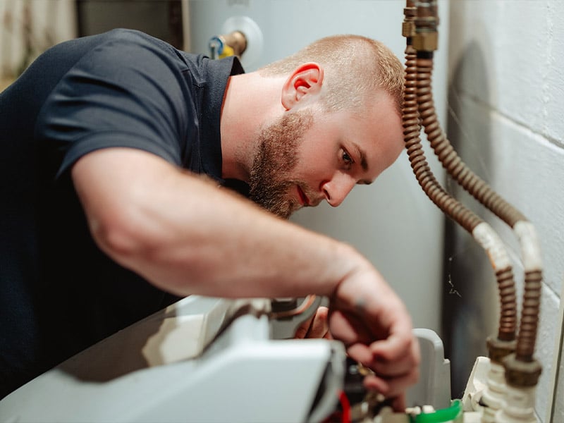A man repairing a water heater, focused on the task.